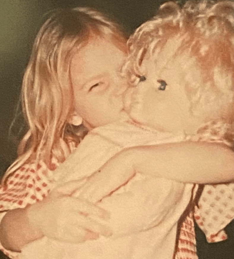 The author as a little girl tightly hugging and kissing her Molly doll.